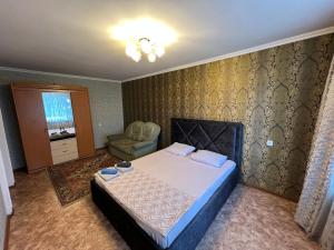 ein Schlafzimmer mit einem Bett und einem Stuhl in der Unterkunft Стандарт Камзина 74 г. Павлодар in Pawlodar