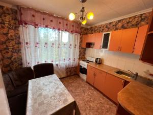 una pequeña cocina con mesa, fregadero y ventana en Стандарт Камзина 74 г. Павлодар, en Pavlodar