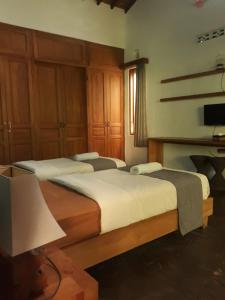 a bedroom with two beds and a television in it at Pondok IJo Villa in Timuran