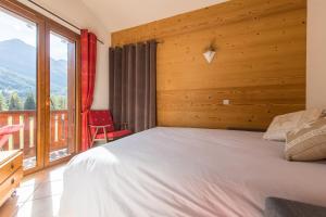 ein Schlafzimmer mit einem Bett und einem großen Fenster in der Unterkunft Fleurs et Neige in Lanslevillard
