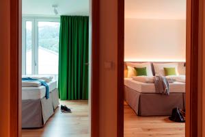 een slaapkamer met 2 bedden en een groen gordijn bij All-Suite Resort Ötztal in Oetz