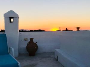 eine Vase, die auf einer Wand sitzt, mit dem Sonnenuntergang im Hintergrund in der Unterkunft Mandarin traditional house with outdoor jacuzzi in Koskinou