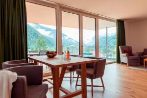 a dining room with a table and chairs and a large window at All-Suite Resort Ötztal in Oetz