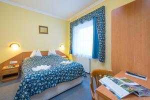 a bedroom with a bed and a desk and a window at Kikelet Club Hotel in Miskolctapolca