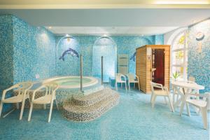 Cette chambre dispose d'une baignoire, d'une table et de chaises. dans l'établissement Kikelet Club Hotel, à Miskolctapolca
