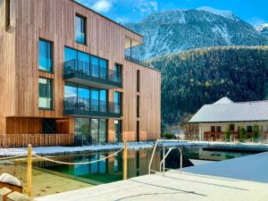 a building with a pool and mountains in the background at All-Suite Resort Ötztal in Oetz