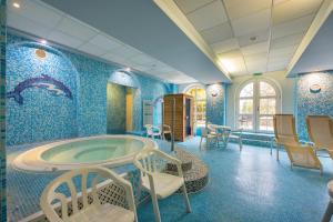 Habitación con paredes azules y baño con bañera. en Kikelet Club Hotel en Miskolctapolca