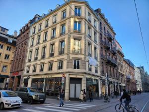 un grande edificio in una strada cittadina con persone che attraversano la strada di Résidence 12 Rue de la Mesange - City Center a Strasburgo