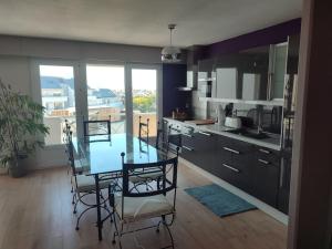 a kitchen with a glass table and chairs in it at Grand T2 lumineux Viarme/Talensac avec parking in Nantes