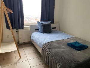 a bedroom with a bed with blue sheets and a window at Atlantis Appartement in Egmond aan Zee