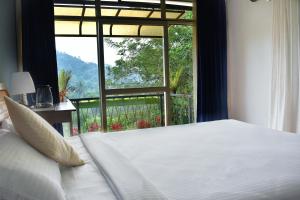 a bedroom with a white bed and a large window at Raymond's Holiday Homes in Vythiri