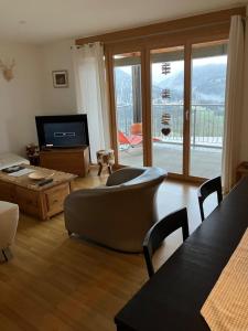 ein Wohnzimmer mit einem Sofa, einem Tisch und einem TV in der Unterkunft Vazerol in Lenzerheide