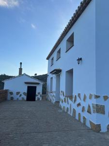 een wit gebouw met een stenen muur ernaast bij Casa rural huertas largas in Casarabonela