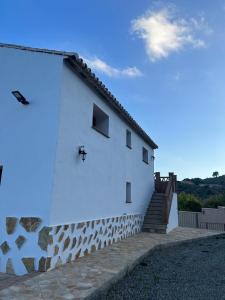 een wit gebouw met een trap aan de zijkant bij Casa rural huertas largas in Casarabonela