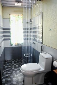 a bathroom with a white toilet and a shower at Raymond's Holiday Homes in Vythiri