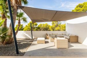 een overdekte patio met een bank, tafels en palmbomen bij Villa in Finestrat in Finestrat