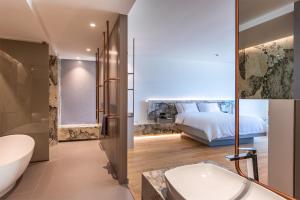 a bathroom with a bed and a tub and a bedroom at Amario Suites Hotel in Aigio