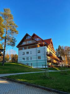 ein großes weißes Gebäude mit braunem Dach in der Unterkunft Apartment RIVIERA Lipno 511 in Lipno nad Vltavou