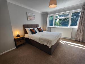 a bedroom with a bed with a nightstand and two windows at Piping Green 5 bedroom House in Winchester