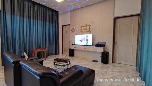 a living room with a couch and a television at Siri Nathai Pool Villa สิรินาไทย พูลวิลล่า in Krabi