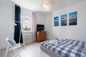 1 dormitorio con 1 cama, TV y silla en Nautic Strandhotel en Sierksdorf