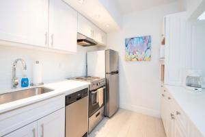 uma cozinha com armários brancos e um frigorífico de aço inoxidável em Beach Living at Island Pine Villas BLSE em George Town