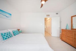 Habitación blanca con cama y tocador de madera. en Beach Living at Island Pine Villas BLSE, en George Town