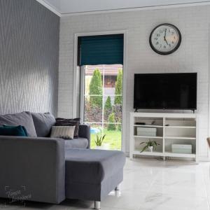 uma sala de estar com um sofá e um relógio na parede em Дом для всех! em Marupe
