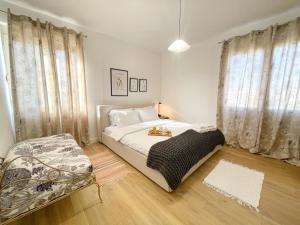 a bedroom with a bed and a chair and windows at Metro Suites in Tirana