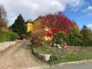 uma casa amarela com uma árvore com folhas vermelhas em Loft mon Soleil em Le Hohwald