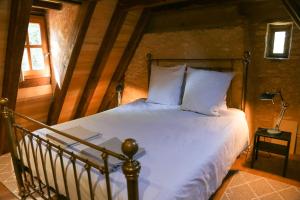 um quarto com uma cama com lençóis brancos e almofadas em La Petite Maison em Le Bugue