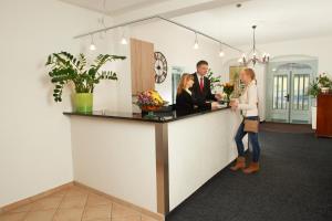 a man and woman standing at a counter in a room at Hotel Erbgericht in Bad Schandau