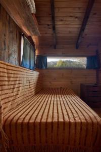 a large bed in a wooden room with a window at Calida Mini Casa in San Carlos de Bariloche
