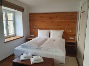 um quarto com uma grande cama branca e uma cabeceira em madeira em Hotel Schierlinger Bräustüberl em Schierling