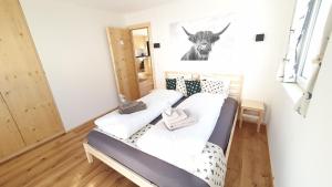 a bed in a room with a picture of a cow on the wall at Yeti Lodge in Sedrun