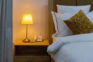 a bed with a lamp and a phone on a night stand at Quest Boutique Hotel in Gwarinpa