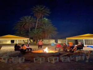 扎戈拉的住宿－Bivouac Draa，一群人晚上坐在火炉旁