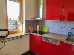 een keuken met rode kasten en een laptop op het aanrecht bij Apartment Arzinol 504 by Interhome in Les Collons