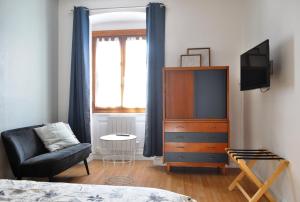 1 dormitorio con TV, silla y vestidor en SEJOURAIXLESBAINS - Appartements Confidence hyper centre calme, en Aix-les-Bains