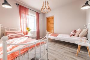a white bedroom with a bed and a chandelier at Bystry Comfort in Bukowina Tatrzańska