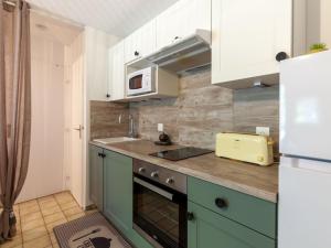 a kitchen with green cabinets and a white refrigerator at Apartment Les Manoirs de la Côte by Interhome in Varaville
