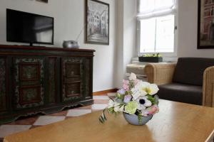 una sala de estar con un jarrón de flores sobre una mesa en Appartamento La Contrada, en Trento