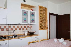 cocina con armarios blancos, mesa y fregadero en Appartamento La Contrada, en Trento