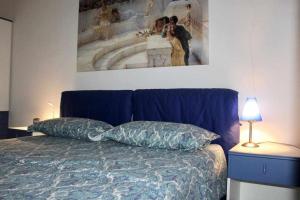 1 cama azul con 2 almohadas y una pintura en la pared en Appartamento La Contrada, en Trento