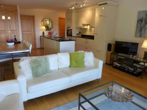 Apartment Orana by Interhome في كرانس مونتانا: غرفة معيشة مع أريكة بيضاء ومطبخ