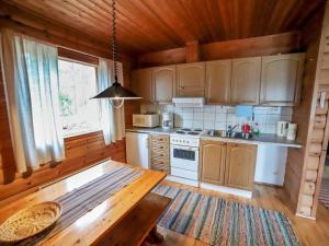 eine Küche mit Holzschränken und einem Tisch in einer Hütte in der Unterkunft Holiday Home Mäkitupa 2 by Interhome in Kuusamo