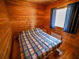 ein Schlafzimmer mit einem Bett in einem Holzzimmer in der Unterkunft Holiday Home Mäkitupa 2 by Interhome in Kuusamo