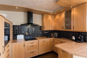 a kitchen with wooden cabinets and a black tiled wall at Hello Zeeland - Appartement Loverendale 31 in Domburg