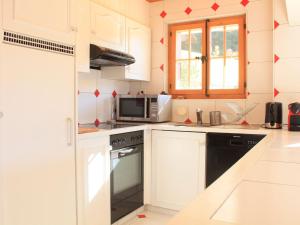 a kitchen with white cabinets and a black appliance at Apartment Rose des Vents 4 by Interhome in Villars-sur-Ollon