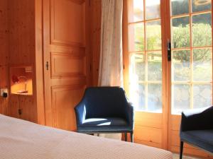 um quarto com uma cama, uma cadeira e uma janela em Apartment Rose des Vents 4 by Interhome em Villars-sur-Ollon
